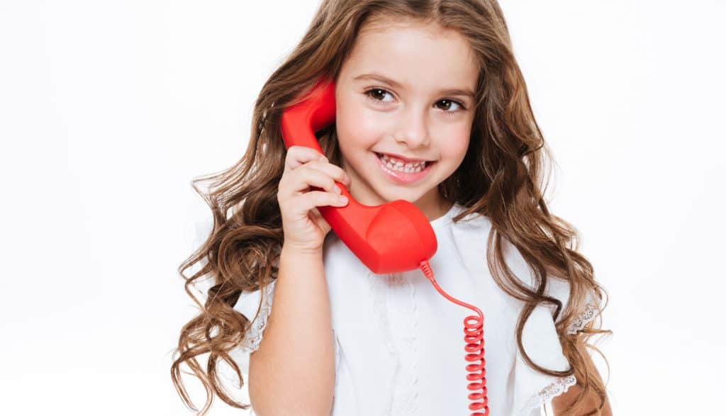 A child holding a red phone on her right ear.