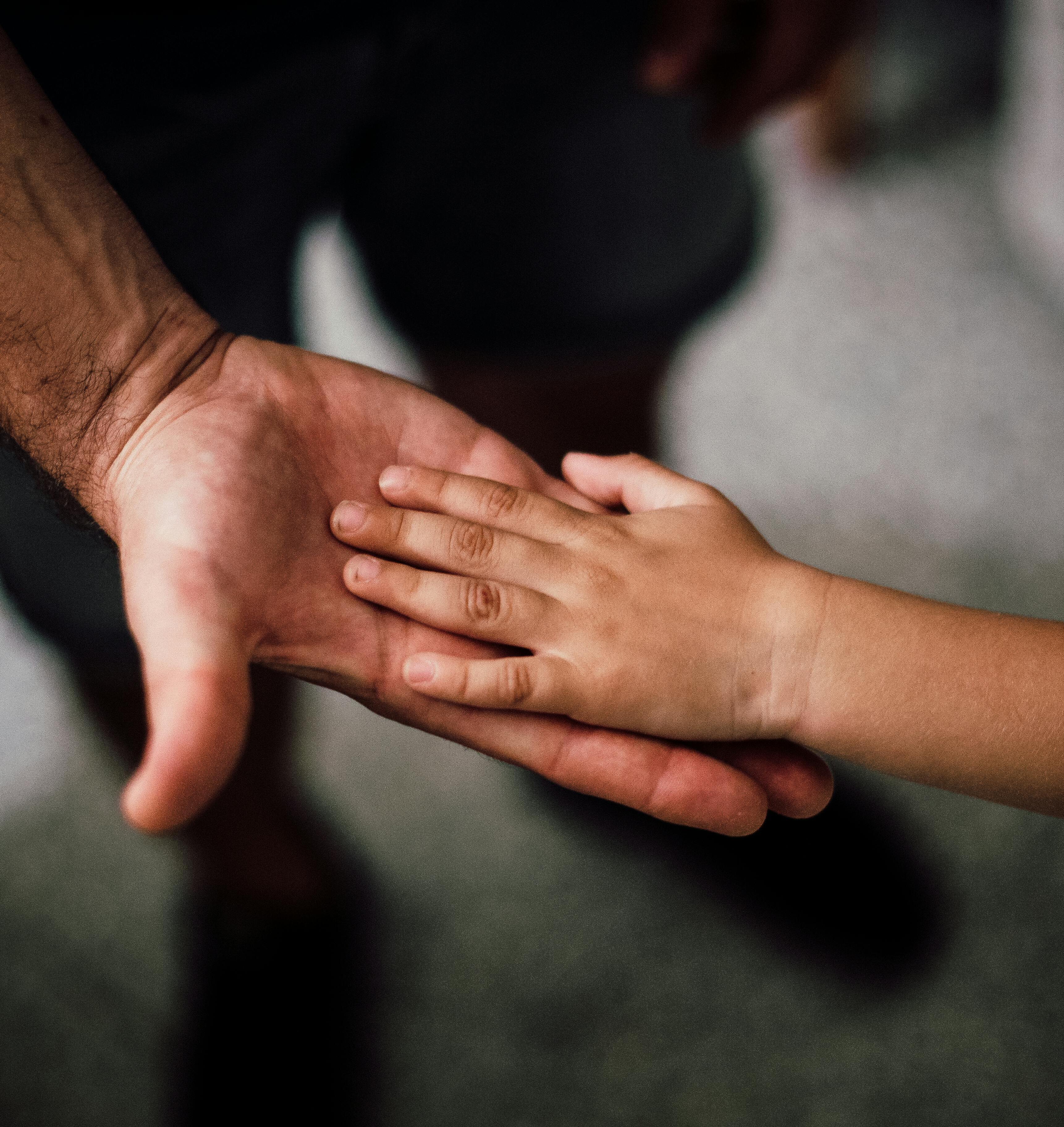 A child's hand on an adult's hand.